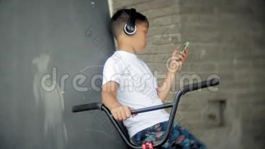 男孩坐在BMX自行<strong>车上</strong>，听智能手机上的<strong>音乐</strong>